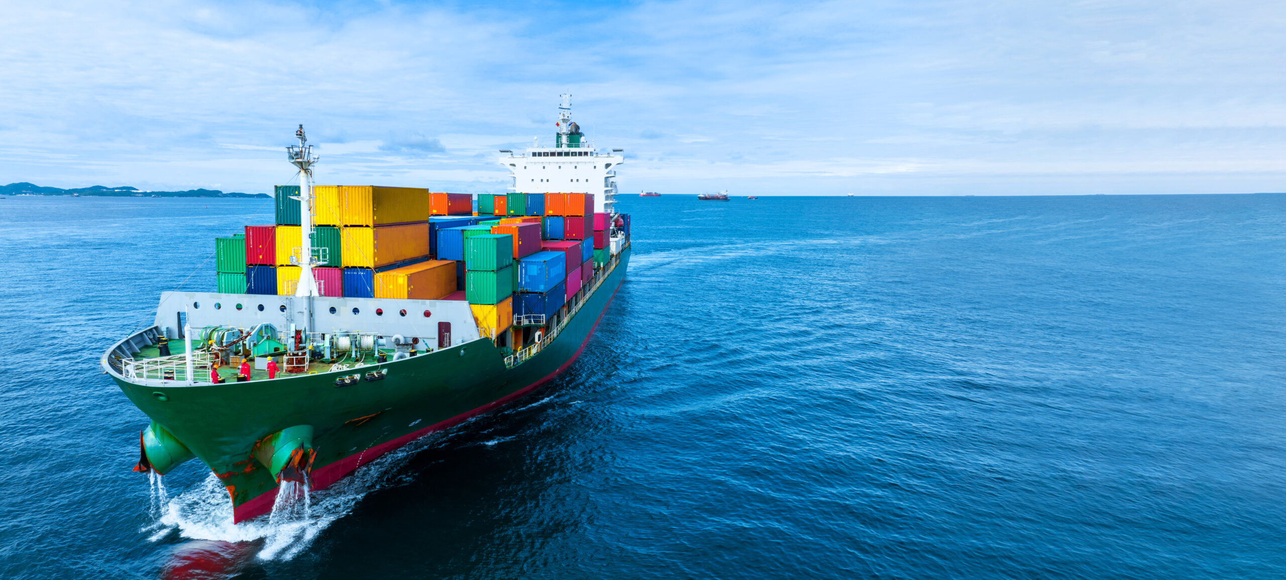 Aerial side view of cargo ship carrying container and running fo